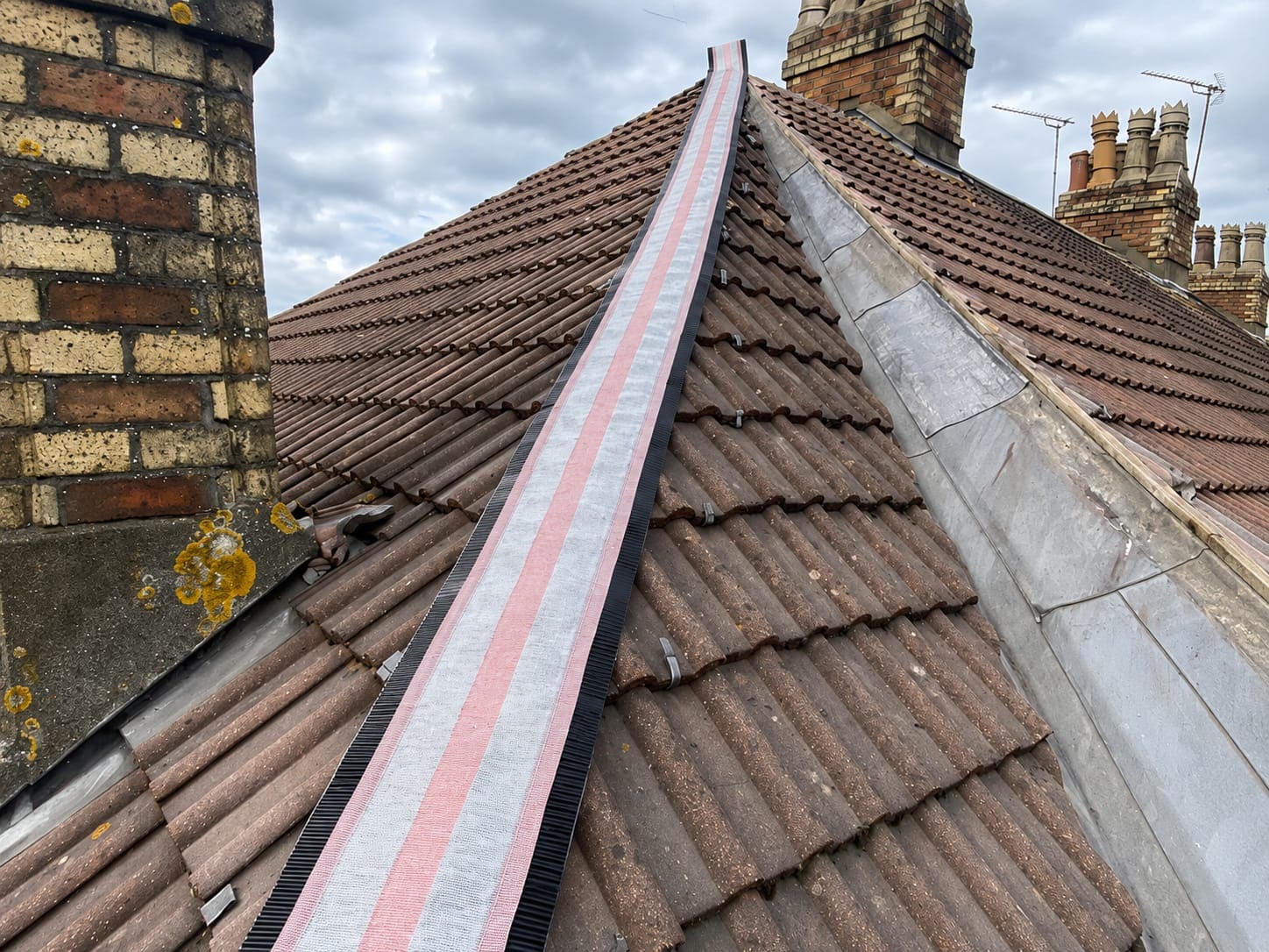 Dry ridge and hip system being fitted along the hip of a tiled roof