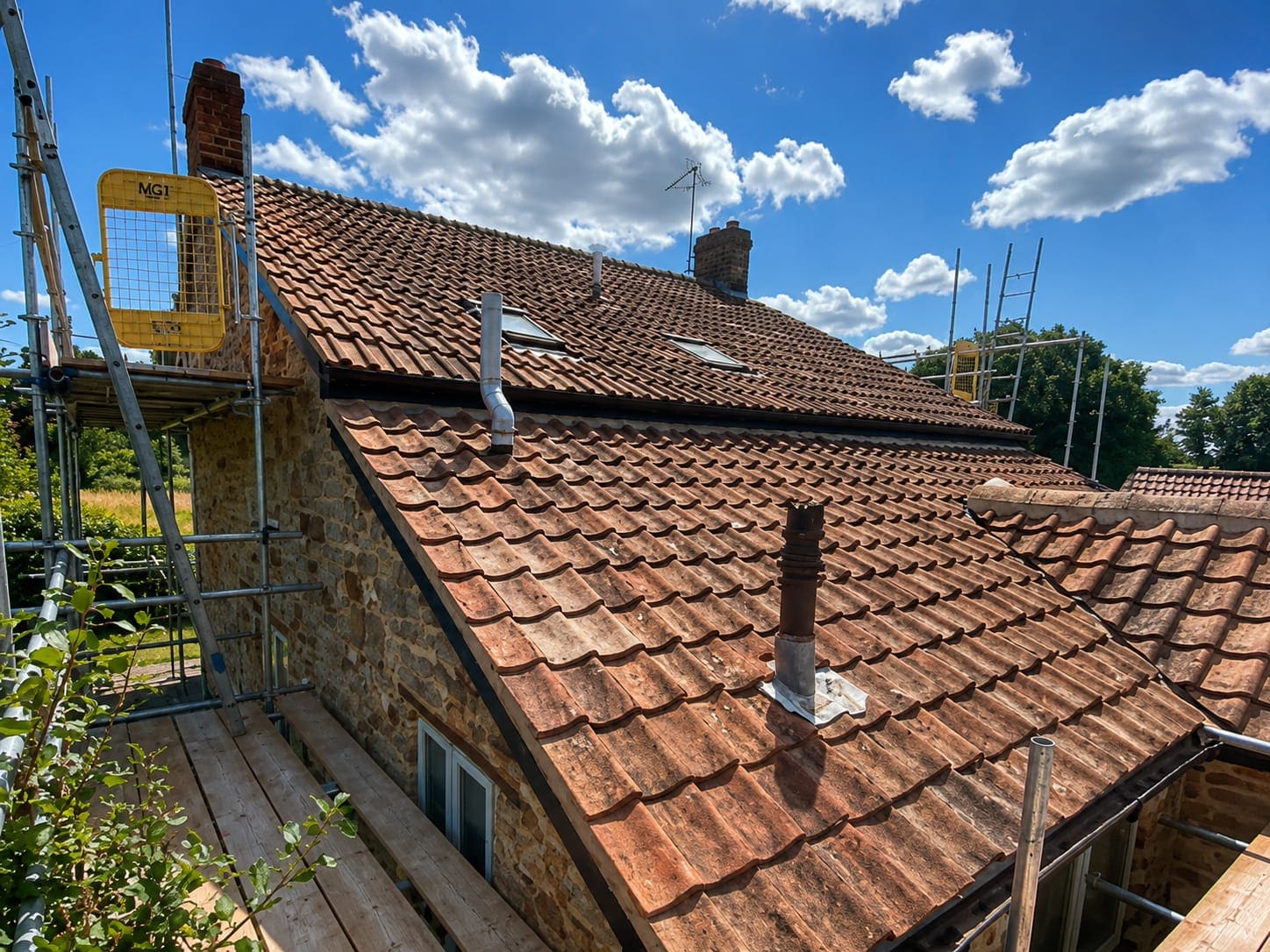 Roof-level view across a clay pantile roof with rooflights and scaffold in place