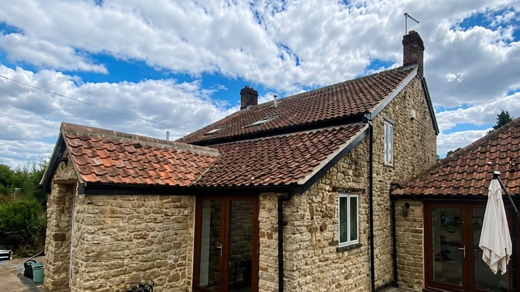 Completed clay pantile roof on a stone cottage, with the patio and garden in front